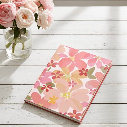 Floral notebook on a wooden surface with pink roses in the background