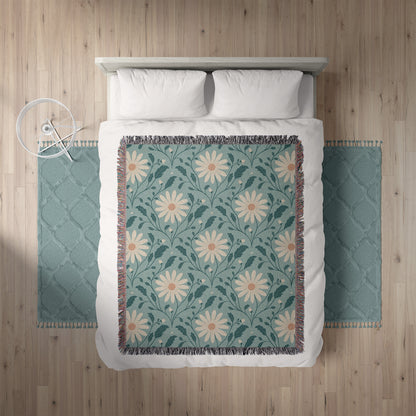 Floral patterned throw blanket on a bed with teal rugs on either side.