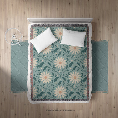 Floral patterned throw blanket on a bed with white pillows.
